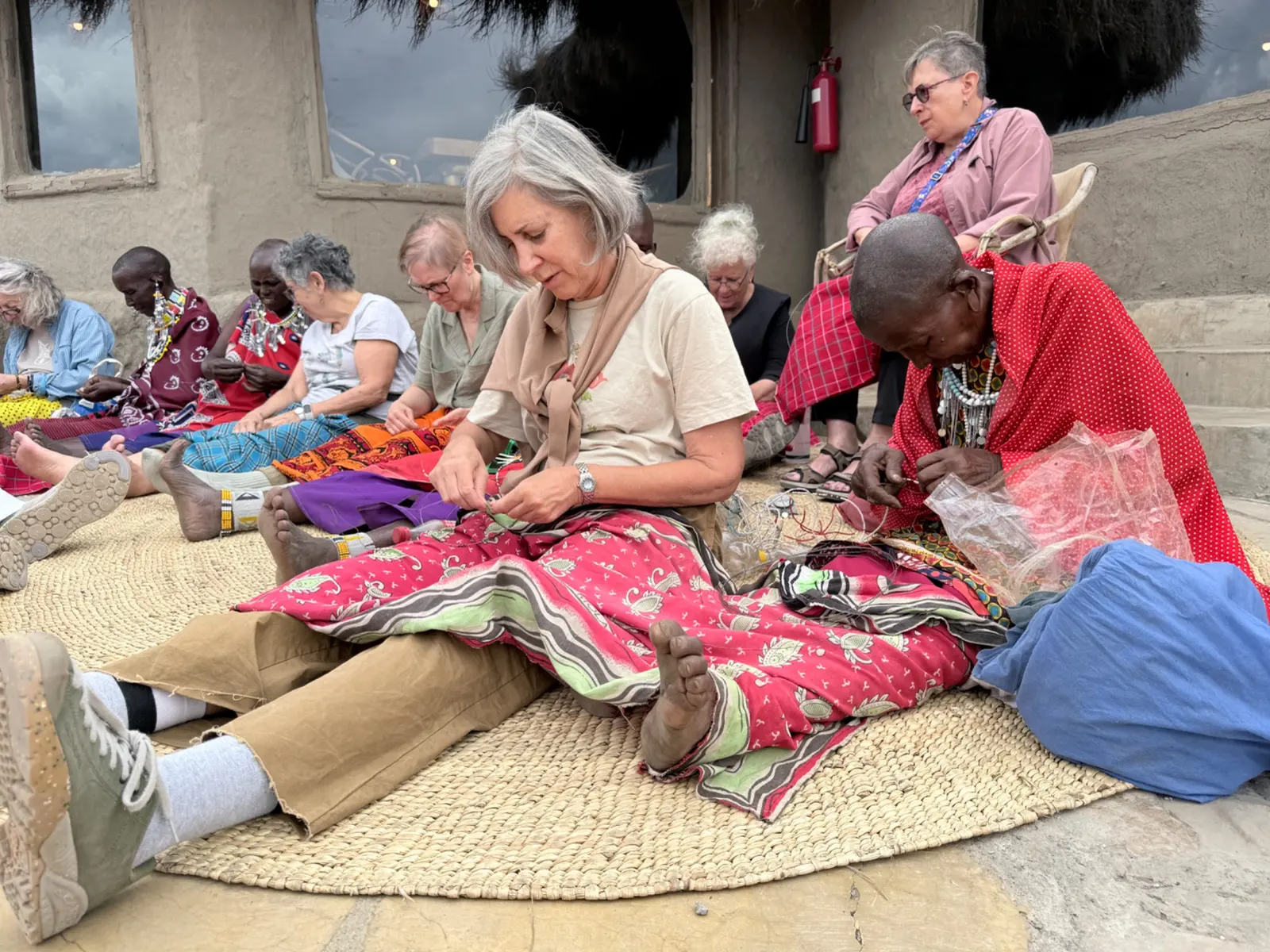 Visitors and Maasai women sharing skills through beadwork in Tanzania